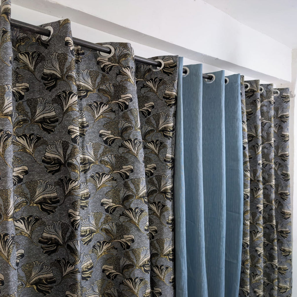 Curtains with a floral pattern and plain blue sections on a white background