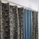 Curtains with a floral pattern and plain blue sections on a white background