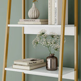 White shelf with gold legs displaying books and decorative items against a green wall.