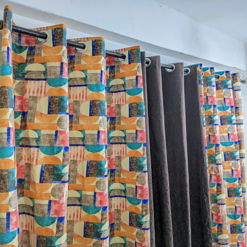 Colorful geometric patterned curtains on a rod against a white wall.