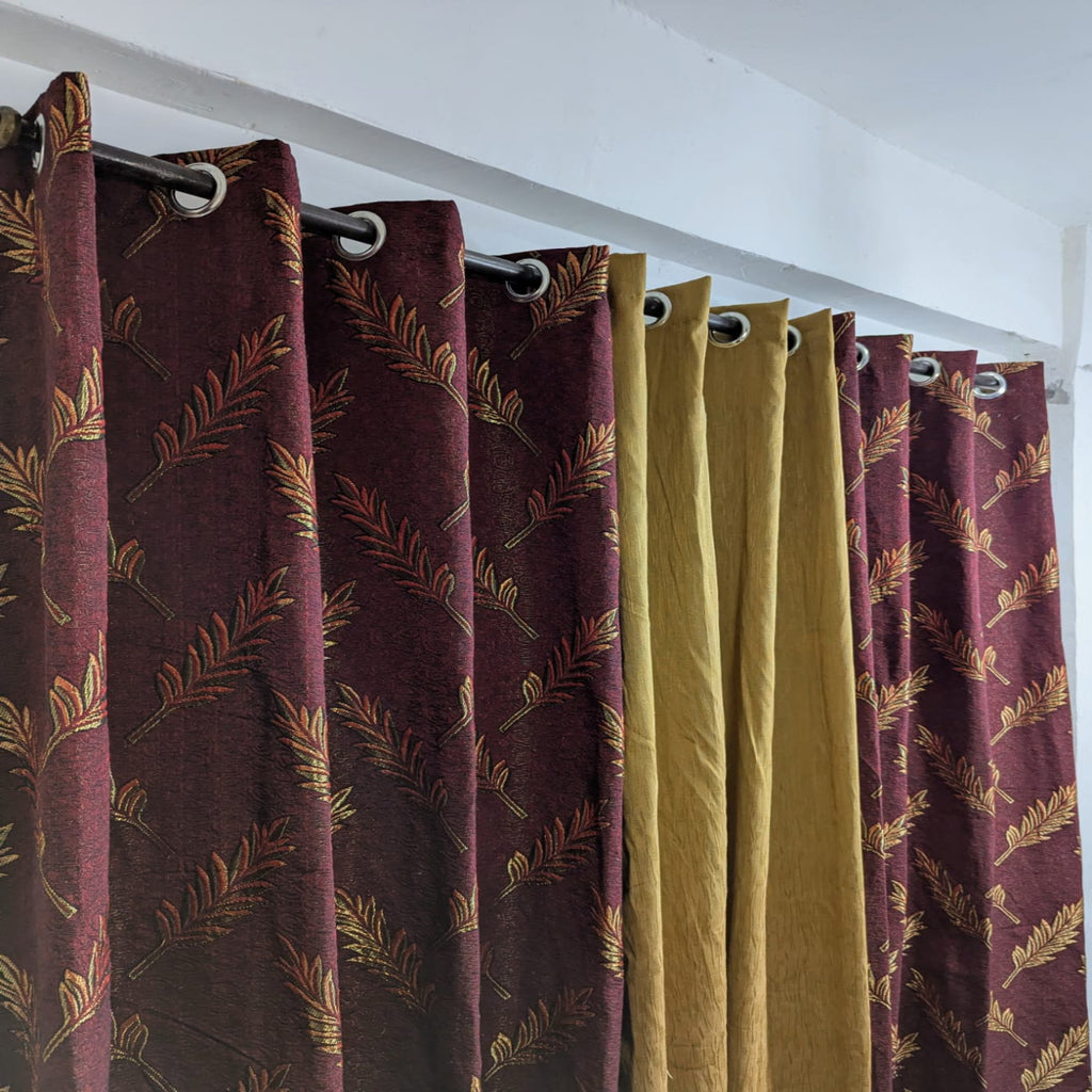Curtains with leaf pattern in maroon and gold on a white background