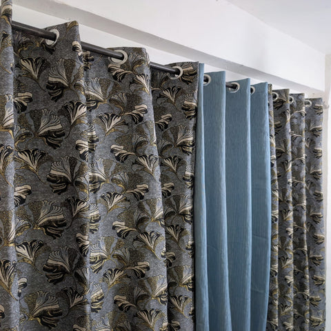 Curtains with a floral pattern and plain blue sections on a white background