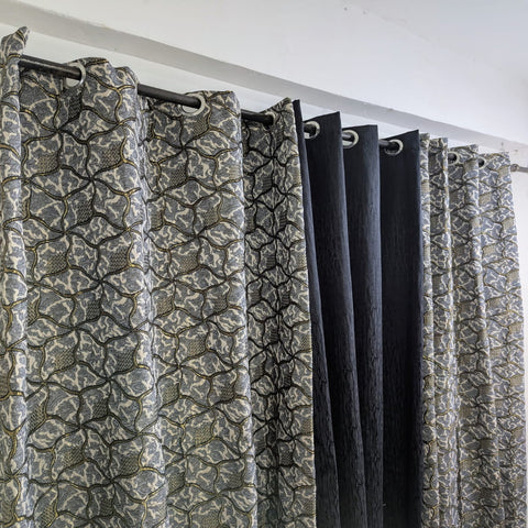 Patterned curtains with a black rod on a white wall background