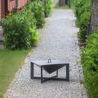 Modern black outdoor table on a gravel path with greenery