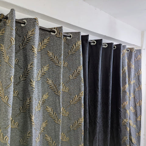 Gray curtains with gold leaf pattern hanging in a room.