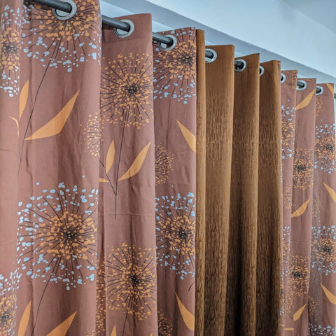Brown curtains with floral pattern hanging in a room.