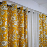 Yellow floral curtains with a white curtain in between on a wooden rod.