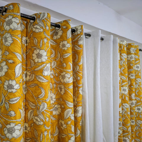 Yellow floral curtains with a white curtain in between on a wooden rod.