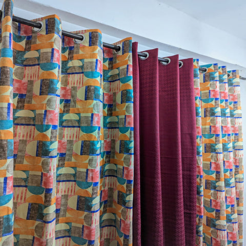 Colorful patterned curtains hanging on a rod against a white wall.