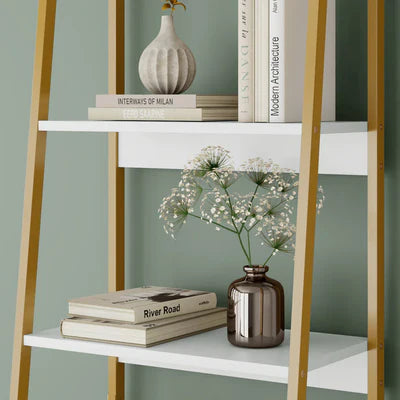 White shelf with gold legs displaying books and decorative items against a green wall.