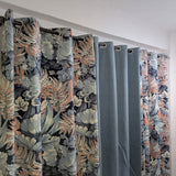 Pair of floral-patterned curtains with a plain gray curtain in between on a white wall.