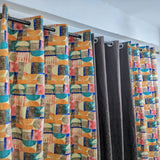 Colorful geometric patterned curtains on a rod against a white wall.