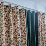 Floral and solid color curtains hanging on a rack against a white wall.