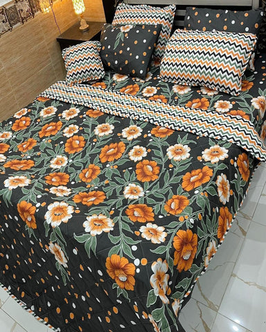 Floral patterned bedspread with orange flowers on a black background, featuring matching pillows.