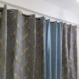Gray curtains with gold leaf pattern hanging on a white rod.