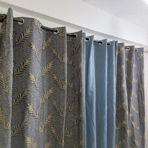 Gray curtains with gold leaf pattern hanging on a white rod.