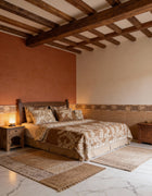 Bedroom with wooden beams, patterned bedspread, and side tables.